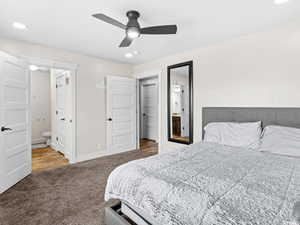 Carpeted bedroom featuring ensuite bath, baseboards, and a ceiling fan