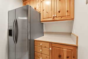 Kitchen featuring stainless steel refrigerator with ice dispenser, light countertops, and light brown cabinetry