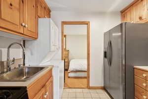 Kitchen featuring stainless steel fridge with ice dispenser, a sink, light countertops, light tile patterned floors, and baseboards