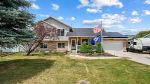 Split level home with brick siding, a shingled roof, concrete driveway, an attached garage, and roof mounted solar panels