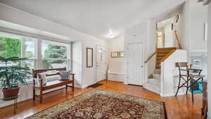 Foyer featuring wood finished floors, stairs, baseboards, and vaulted ceiling