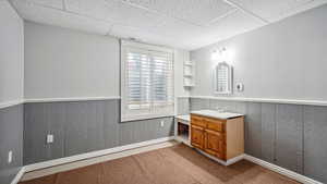 Bathroom with vanity, a paneled ceiling, a wainscoted wall, and baseboards