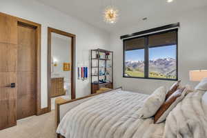 Bedroom with light colored carpet, ensuite bathroom, a mountain view, and recessed lighting