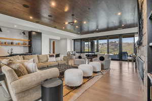Living room featuring light wood-style floors, a mountain view, recessed lighting, wood ceiling, and wet bar