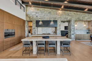 Kitchen featuring modern cabinets, a kitchen breakfast bar, light wood-type flooring, a fireplace, and open floor plan