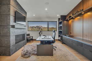 Office featuring light wood-type flooring, recessed lighting, and a glass covered fireplace