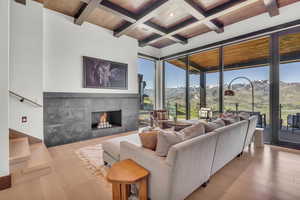 Living area with beamed ceiling, a tile fireplace, a mountain view, coffered ceiling, and light wood-type flooring