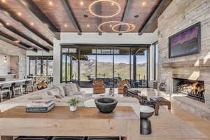 Living room featuring a chandelier, wood ceiling, a stone fireplace, and wood finished floors