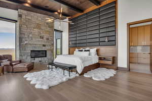 Bedroom with ensuite bath, a wooden ceiling with exposed beams, wood finished floors, and a fireplace