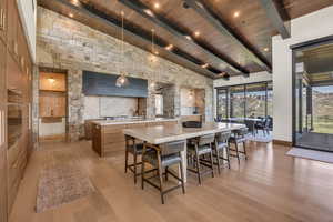 Dining room with light wood-style floors, high vaulted ceiling, a wood ceiling with exposed beams, and a mountain view