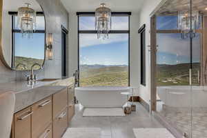 Bathroom featuring a chandelier, vanity, and a freestanding tub
