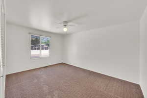 Spare room featuring a ceiling fan, carpet floors, and baseboards