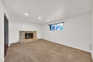 Unfurnished living room with carpet, recessed lighting, a fireplace, and baseboards