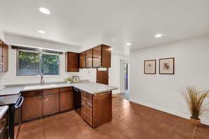 Kitchen with black appliances, a sink, a peninsula, light countertops, and healthy amount of natural light