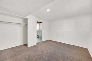 Unfurnished bedroom with a textured ceiling, carpet flooring, recessed lighting, and a closet