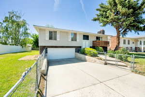 Raised ranch featuring driveway, an attached garage, a chimney, and a gate