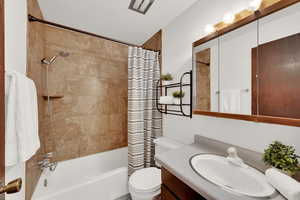 Full bathroom featuring shower / bath combo with shower curtain, vanity, and toilet