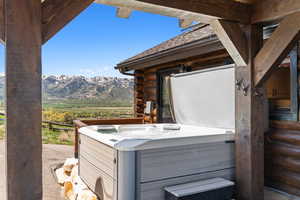 Exterior view of a jacuzzi, a mountainous background, a downspout, log siding, and gutters