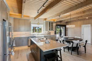 Kitchen featuring stainless steel appliances, light wood-style floors, decorative backsplash, light stone countertops, and wooden walls