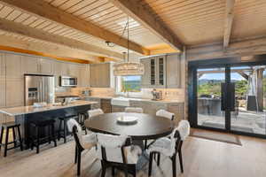 Dining space with light wood-type flooring, wood ceiling with exposed beams, a chandelier, and french doors