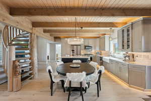 Dining area featuring wood ceiling with exposed beams, stairway, a chandelier, and light wood-style floors