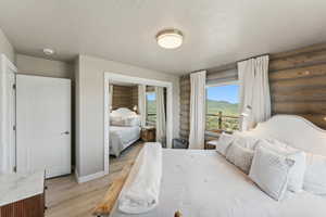 Bedroom featuring light wood-style floors, log walls, baseboards, a mountain view, and a textured ceiling