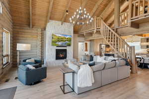 Living area featuring wood ceiling with exposed beams, stairway, high vaulted ceiling, a chandelier, and a fireplace