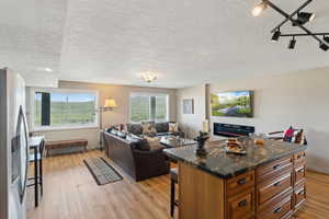 Living room with light wood finished floors, a textured ceiling, and baseboards