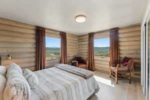 Bedroom featuring log walls, wood finished floors, and a textured ceiling