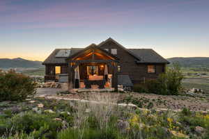 Cabin featuring an outdoor living space, log exterior, roof mounted solar panels, and roof with shingles