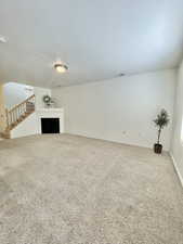 Unfurnished living room with carpet flooring and a textured ceiling