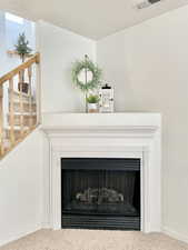 Detailed view of carpet flooring, a fireplace, and baseboards