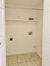 Laundry area featuring washer hookup, electric dryer hookup, light tile patterned floors, and baseboards