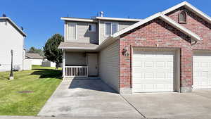 View of front of property featuring brick siding, concrete driveway, a front lawn, and a garage