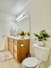 Half bath featuring vanity, tile patterned flooring, and toilet