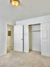 Unfurnished bedroom with carpet, a closet, baseboards, and electric panel