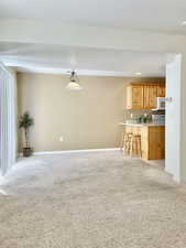 Unfurnished living room with light colored carpet and baseboards