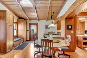 Dining space featuring wood ceiling, light wood finished floors, and a skylight