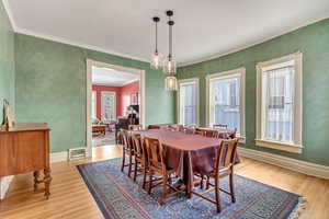 Dining space with wood finished floors, ornamental molding, and baseboards
