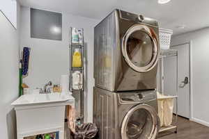 Laundry area featuring stacked washer and clothes dryer and wood finished floors