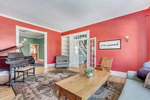 Living room featuring stairway, crown molding, baseboards, wood finished floors, and a chandelier