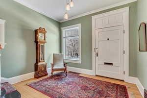 Living area featuring light wood finished floors, baseboards, and ornamental molding