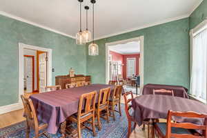 Dining room with wood finished floors, plenty of natural light, crown molding, and baseboards