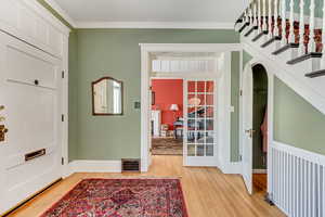 Foyer with light wood-style flooring, baseboards, and ornamental molding