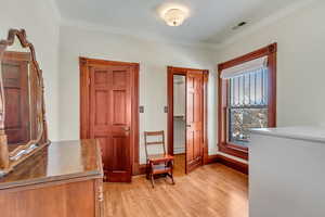 Entrance foyer with light wood finished floors, crown molding, and baseboards