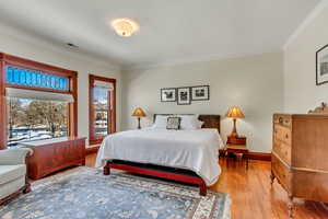 Bedroom with light wood-style floors, crown molding, and baseboards