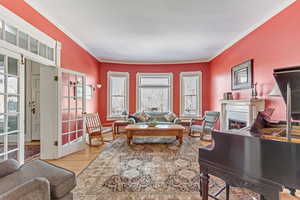 Living room with ornamental molding, a fireplace, and wood finished floors