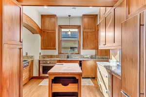 Kitchen with stainless steel appliances, light wood-type flooring, decorative light fixtures, and a sink