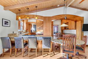 Kitchen featuring light wood-style floors, a peninsula, wood ceiling, stainless steel gas stovetop, and light stone countertops