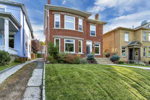 Townhome / multi-family property with a chimney, brick siding, and a front yard